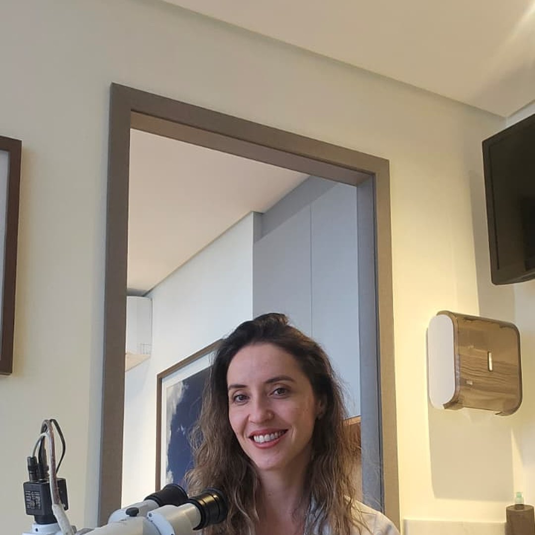 Dra. Talita ao lado do colposcópio em seu consultório